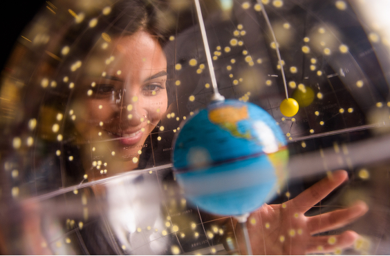 A person looks at a globe surrounded by stars