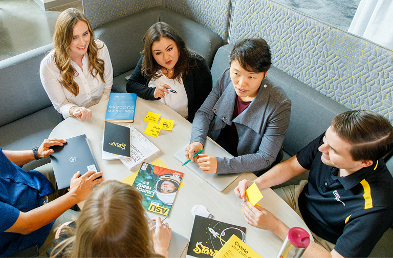 Five people working together at a table.