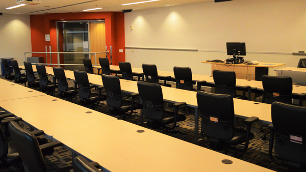 Exploration room set up classroom style with speaker podium and computer at front of room.