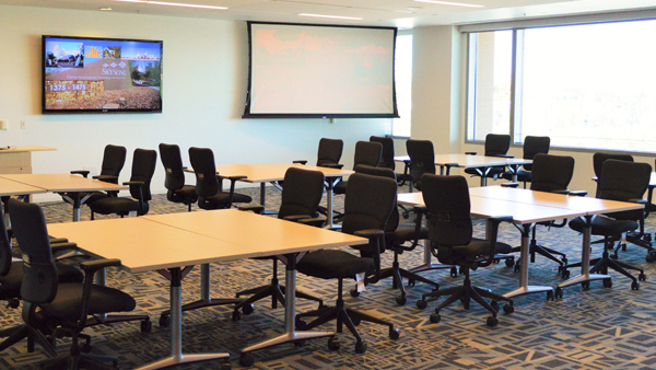 Ingenuity room showing tables and chairs and screen and monitor on wall