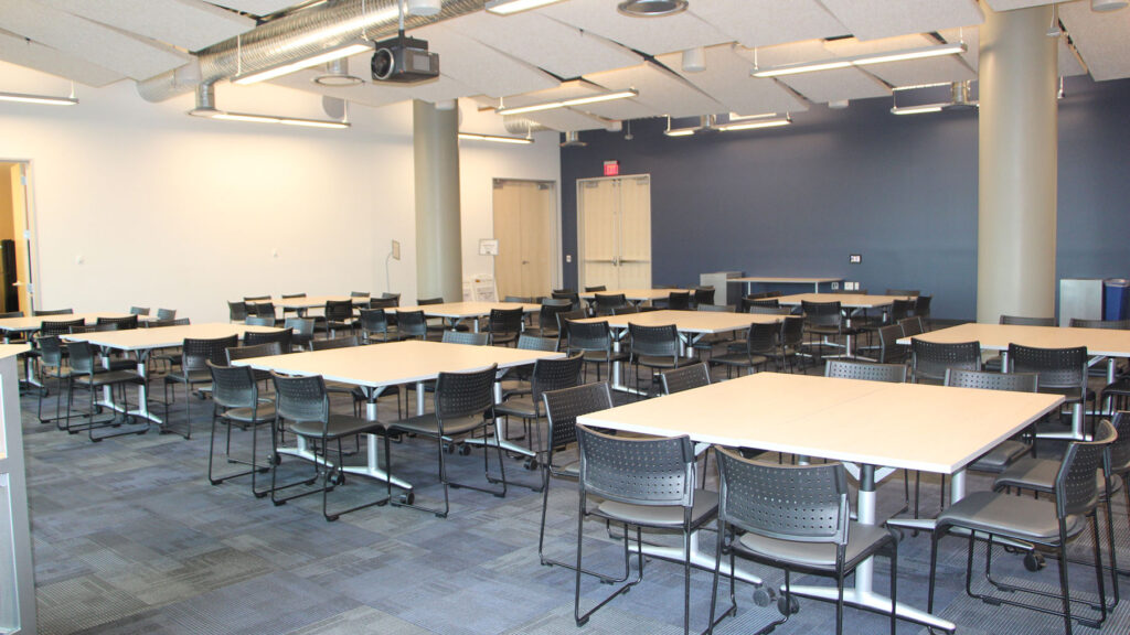 Synergy II room set up as square tables seating 8, with 10 sets., from front of room.
